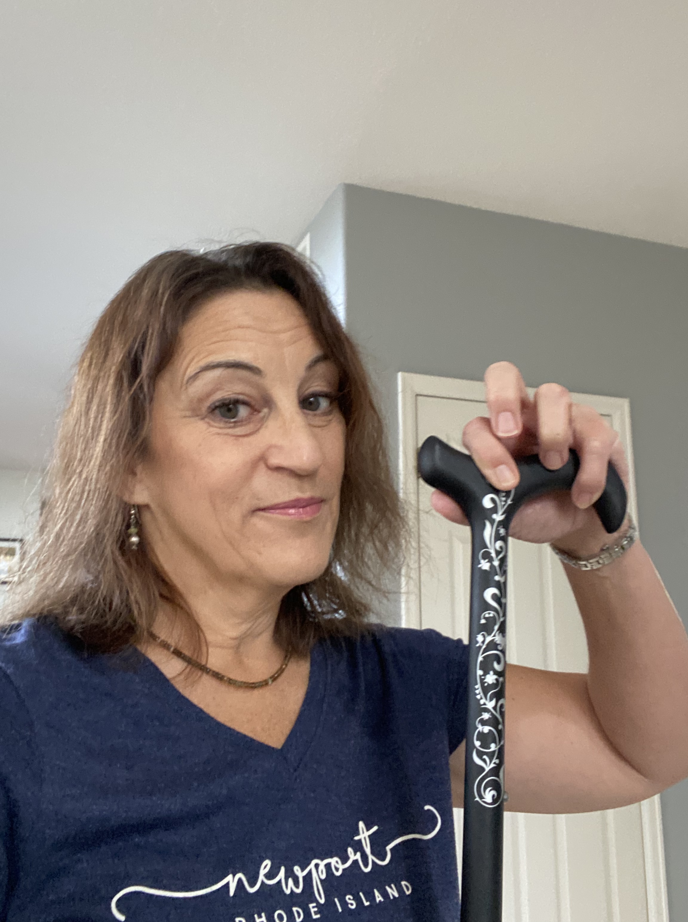 Woman holding up a black cane.